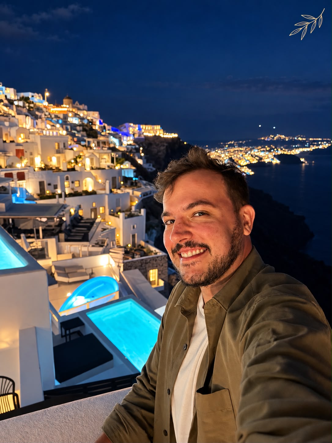 Gabriel Zanette em Oia, Santorini, com as casas iluminadas ao anoitecer